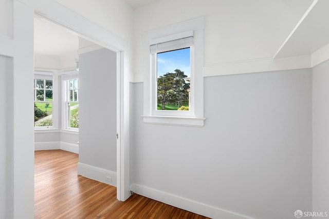bonus room featuring plenty of natural light, wood finished floors, and baseboards