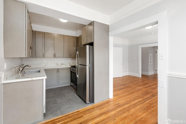 kitchen featuring light countertops, light wood-style floors, stainless steel appliances, and a sink