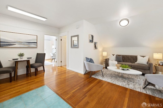 living room featuring lofted ceiling, baseboards, and wood finished floors