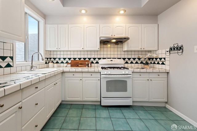 kitchen with white cabinets, white range with gas cooktop, under cabinet range hood, and a sink