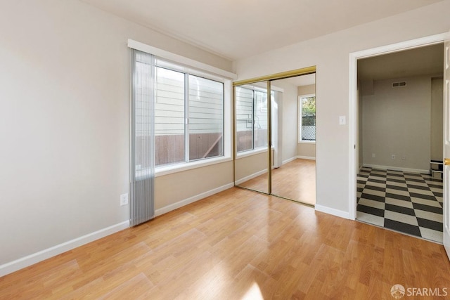 unfurnished bedroom featuring light wood-style flooring, a closet, visible vents, and baseboards