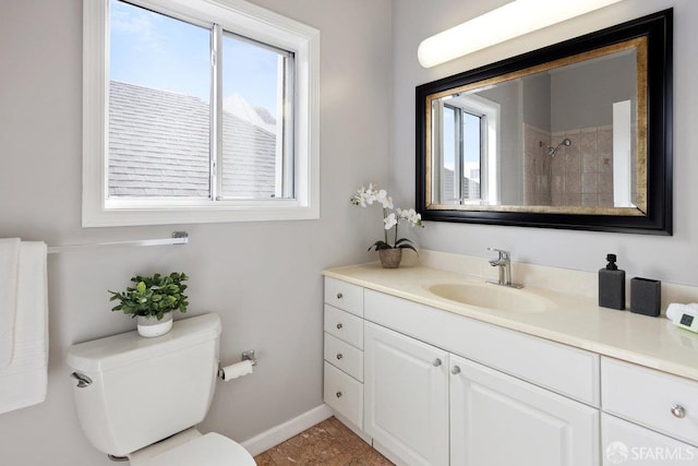 bathroom with baseboards, vanity, toilet, and a healthy amount of sunlight