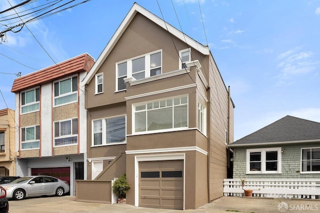 multi unit property featuring a garage, driveway, and stucco siding