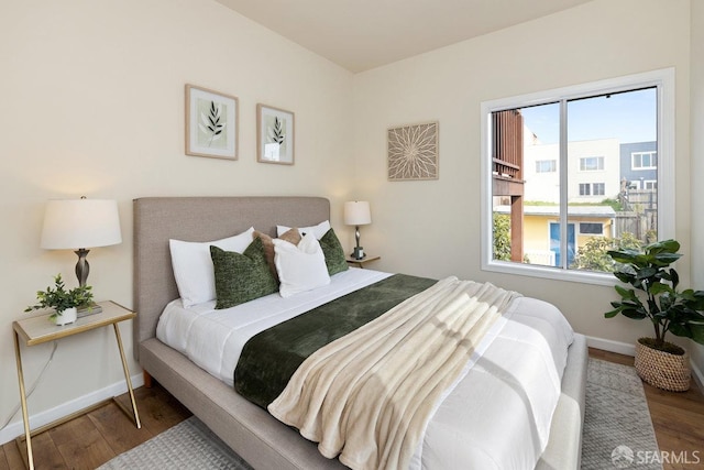 bedroom featuring multiple windows, baseboards, and wood finished floors