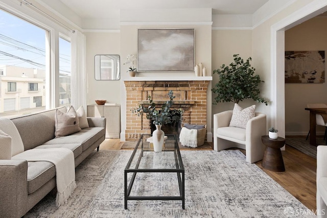 sitting room with baseboards, a fireplace, wood finished floors, and crown molding