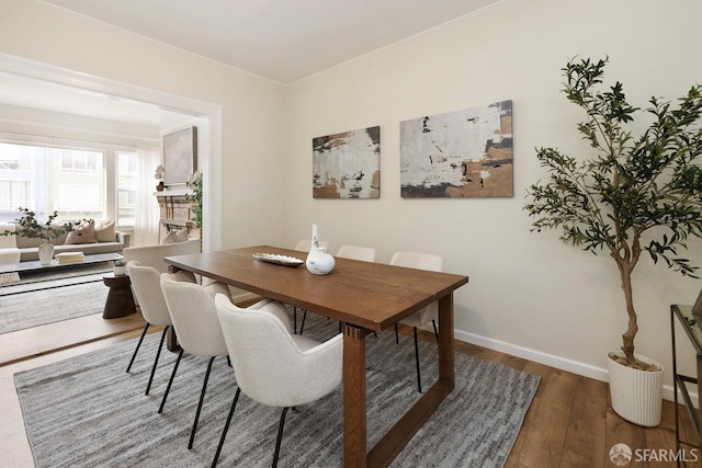 dining room with ornamental molding, wood finished floors, and baseboards