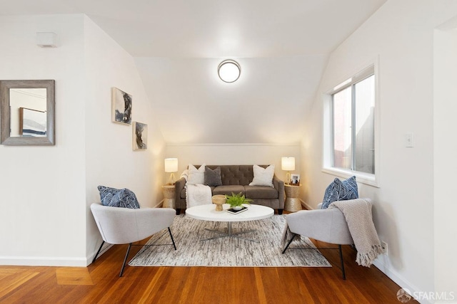 living room featuring lofted ceiling, baseboards, and wood finished floors