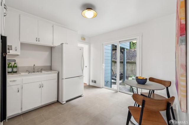 75 Lurline St, San Francisco, CA 94122 - kitchen with a sink, freestanding refrigerator, light countertops, white cabinets, and baseboards