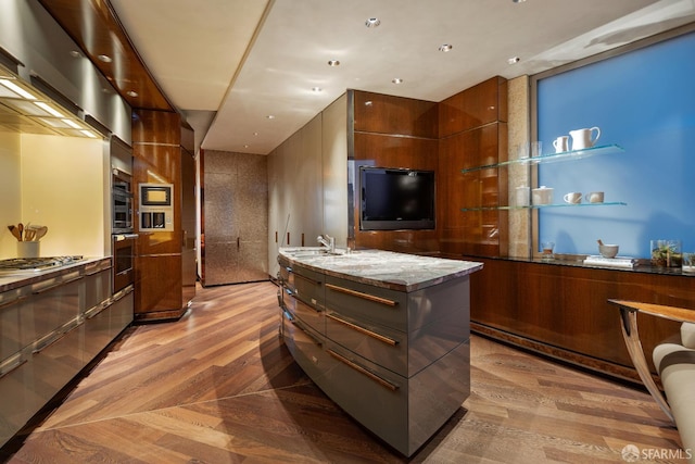 947 Green St Unit 6, San Francisco, CA 94133 - kitchen with modern cabinets, light wood-style flooring, a center island with sink, stainless steel gas stovetop, and a sink