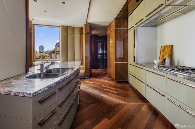 kitchen featuring a sink, dark wood finished floors, light stone counters, a view of city, and gray cabinetry