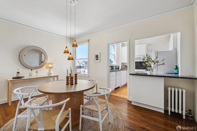 dining area with dark wood-style flooring, ornamental molding, radiator heating unit, and baseboards