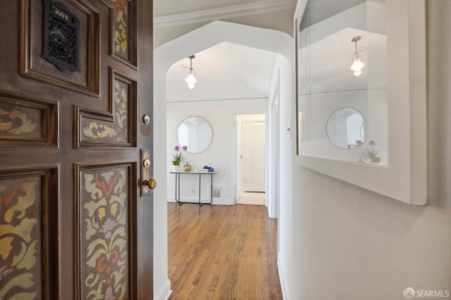 hall with ornamental molding and wood finished floors