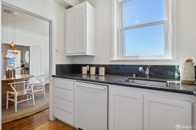 kitchen featuring dishwasher, a sink, white cabinetry, and crown molding