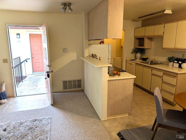 kitchen featuring white refrigerator, kitchen peninsula, sink, and light carpet