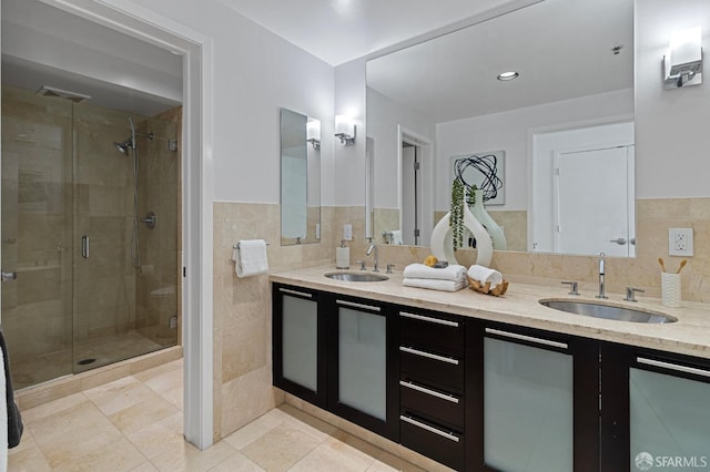 full bathroom featuring double vanity, a sink, tile walls, and a shower stall