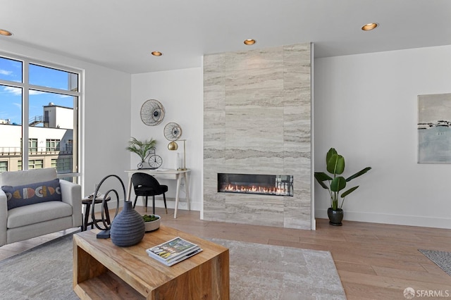 living area with recessed lighting, baseboards, wood finished floors, and a tile fireplace