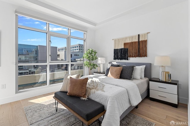 bedroom featuring baseboards, multiple windows, and light wood-style floors