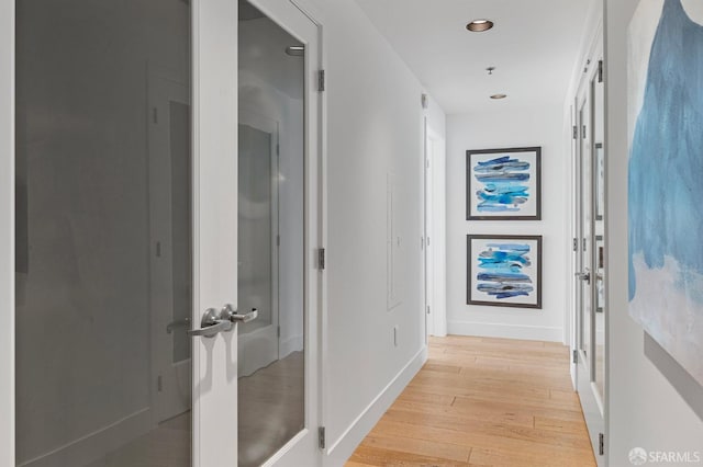 hallway featuring light wood-style floors, baseboards, and recessed lighting