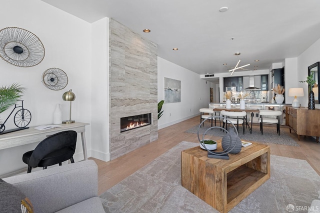 living room featuring recessed lighting, a fireplace, visible vents, baseboards, and light wood-style floors