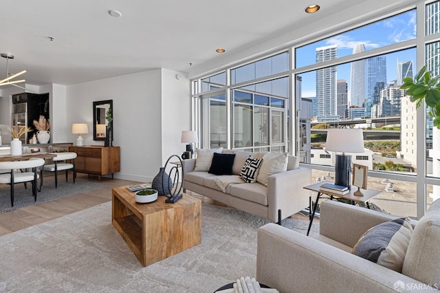 living room with baseboards, wood finished floors, a view of city, a wall of windows, and recessed lighting