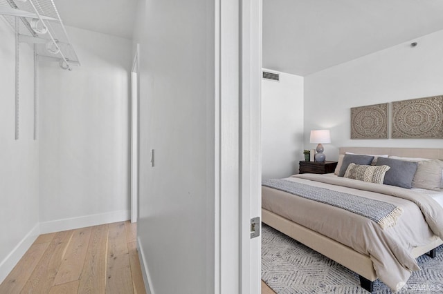 bedroom featuring visible vents, light wood-style flooring, and baseboards