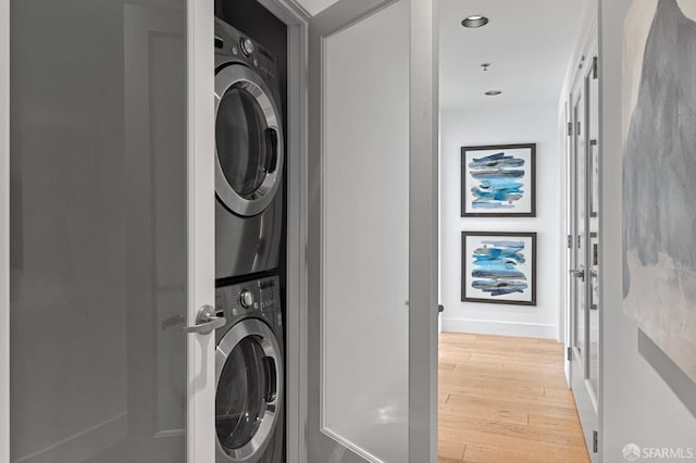 laundry room with recessed lighting, light wood-style floors, stacked washing maching and dryer, laundry area, and baseboards