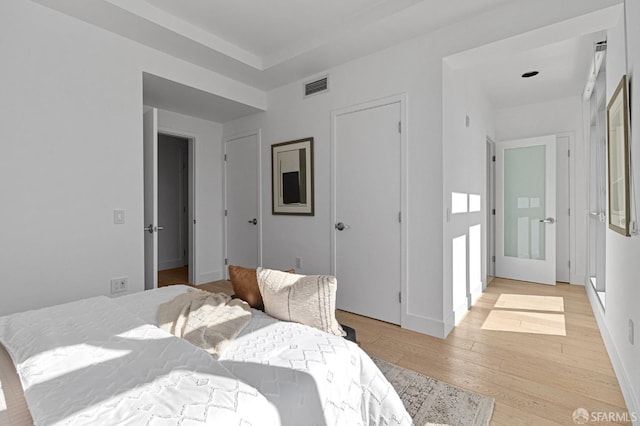 bedroom with light wood-type flooring, visible vents, and baseboards