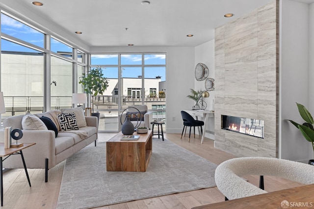 living area featuring recessed lighting, plenty of natural light, wood finished floors, and a high end fireplace