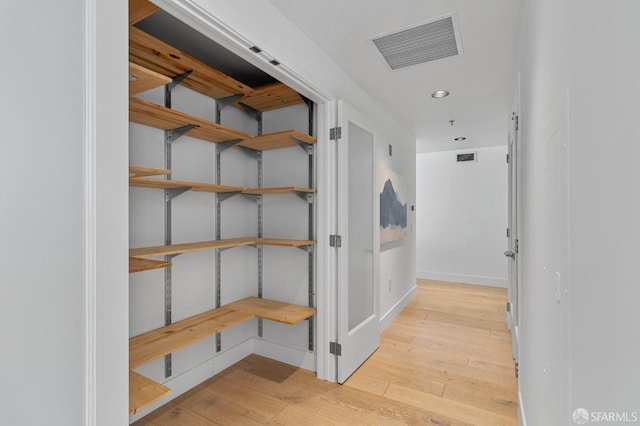 hallway with light wood-style flooring, visible vents, baseboards, and recessed lighting