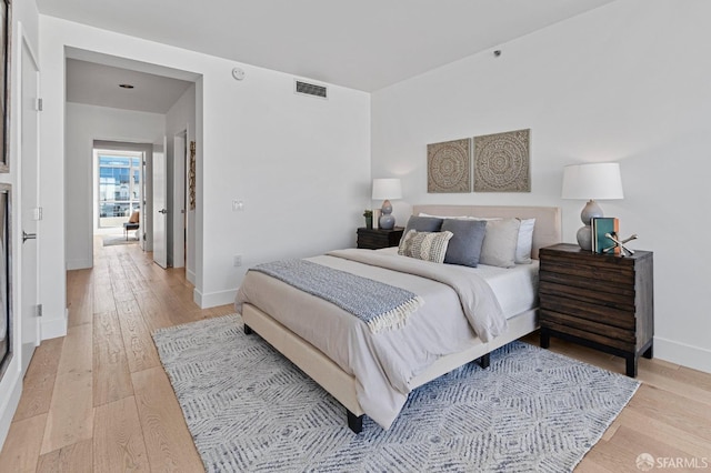 bedroom with light wood-type flooring, baseboards, and visible vents