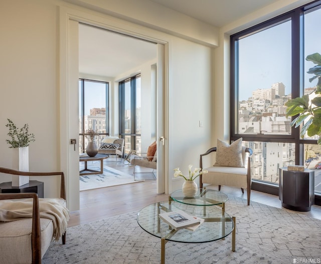 living area with floor to ceiling windows, a city view, and wood finished floors