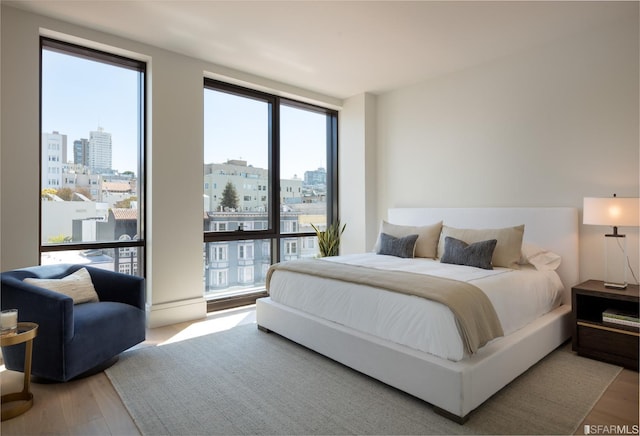 bedroom with light wood-style flooring and a city view