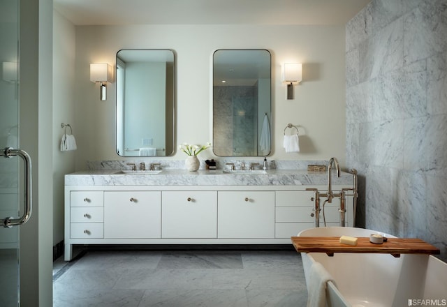 bathroom featuring double vanity, tile walls, and a freestanding bath