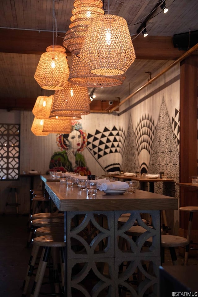 interior space featuring track lighting, wooden ceiling, beam ceiling, and wooden walls