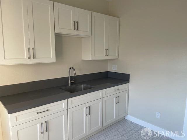 kitchen featuring white cabinetry, light tile patterned floors, and sink