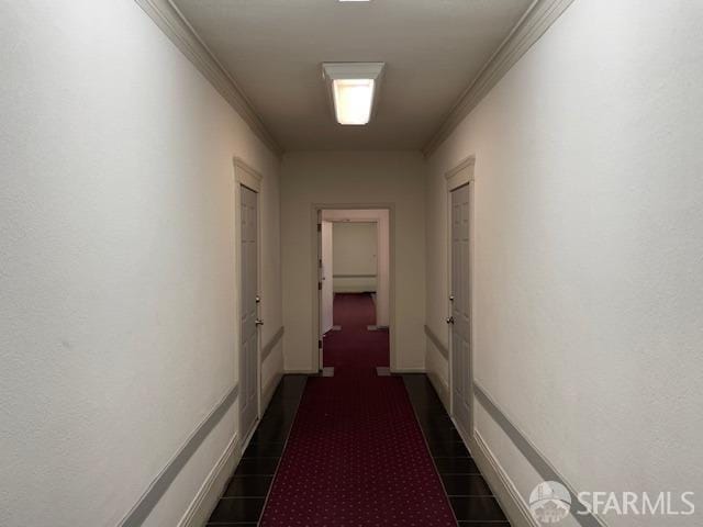 hall with crown molding and dark tile patterned flooring