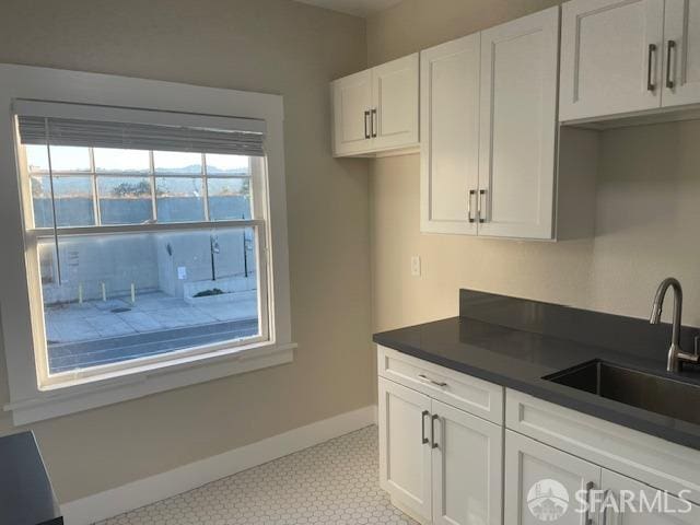 kitchen featuring light tile patterned flooring, sink, and white cabinetry