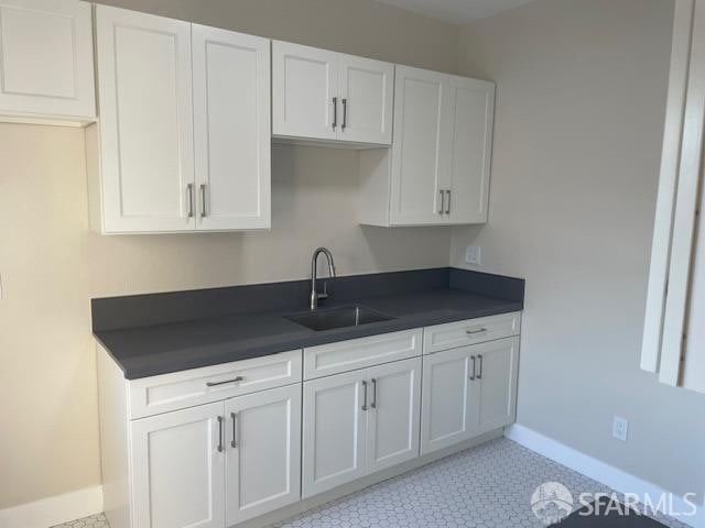 kitchen with sink, light tile patterned floors, and white cabinets