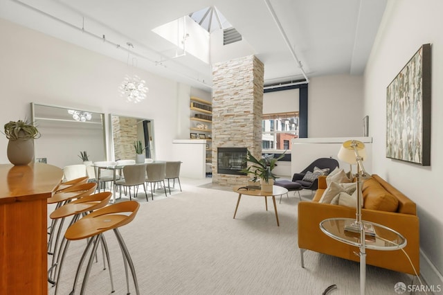 interior space featuring a stone fireplace, a notable chandelier, carpet flooring, and rail lighting