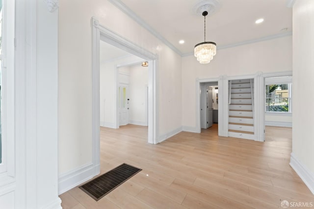 corridor featuring light wood-type flooring, ornamental molding, and a chandelier