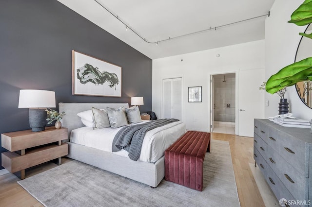 bedroom with rail lighting, light hardwood / wood-style floors, and ensuite bath