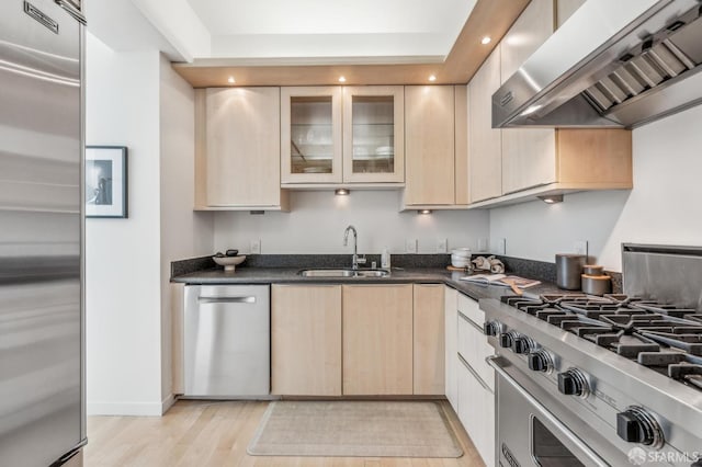 kitchen with light brown cabinetry, appliances with stainless steel finishes, extractor fan, sink, and light wood-type flooring