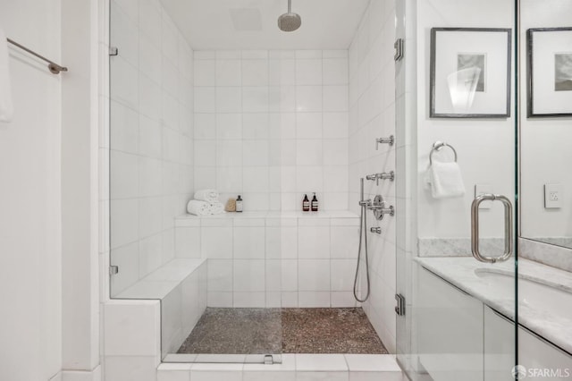 bathroom featuring a shower with shower door and vanity