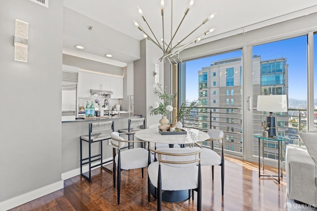 dining room with dark wood-type flooring, plenty of natural light, and a notable chandelier