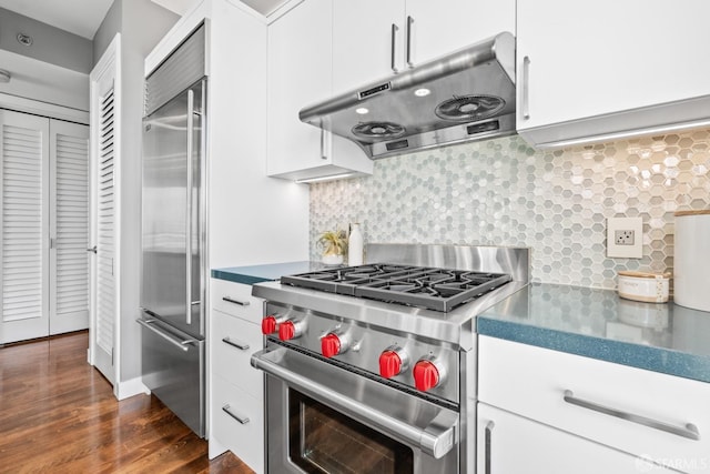 kitchen with dark hardwood / wood-style flooring, premium appliances, backsplash, and white cabinetry