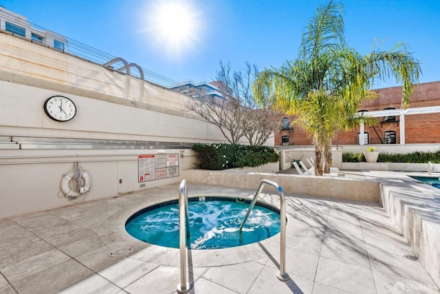 view of swimming pool featuring a hot tub and a patio area