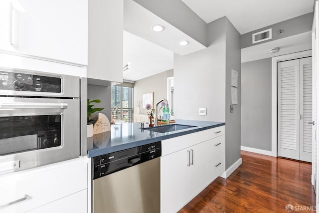 kitchen with dark wood-type flooring, white cabinetry, appliances with stainless steel finishes, and sink