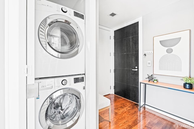 clothes washing area with hardwood / wood-style flooring and stacked washer and clothes dryer