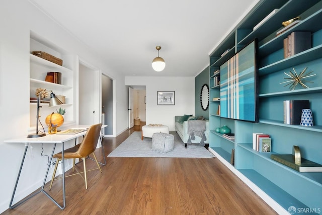 living area featuring built in features, baseboards, and wood finished floors