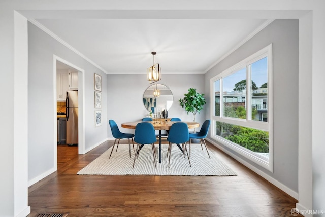 dining area featuring dark wood-style floors, crown molding, and baseboards